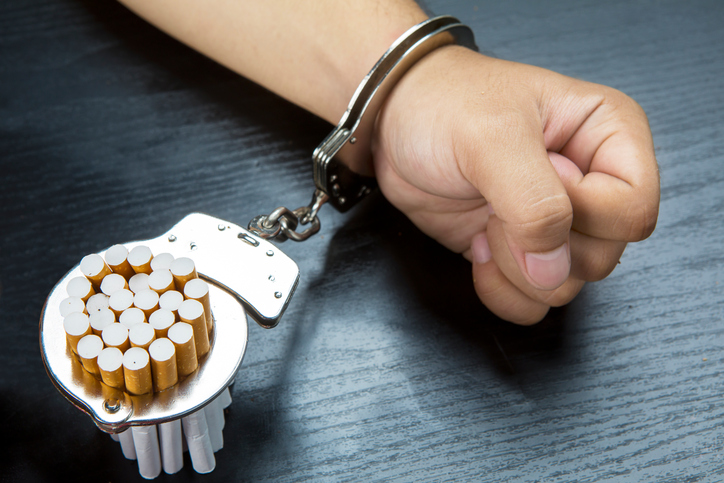 Arm of man and cigarettes with handcuffs